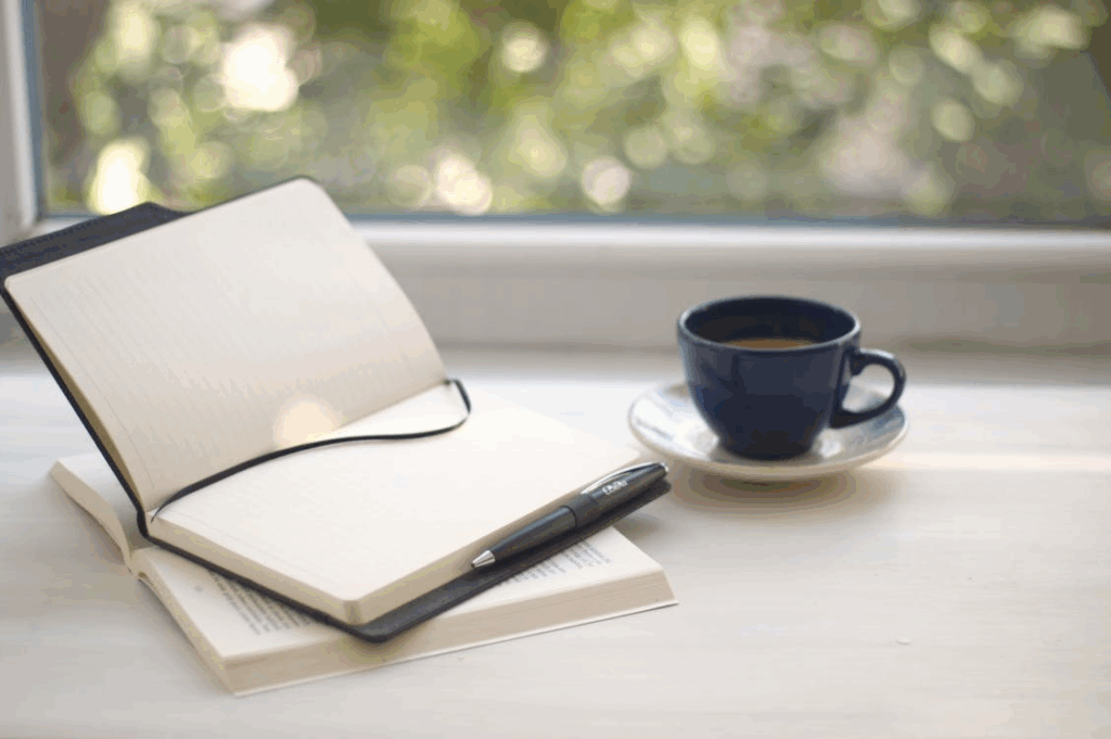 Notebook, pen, and coffee cup for mindful journaling and time perception hacks.