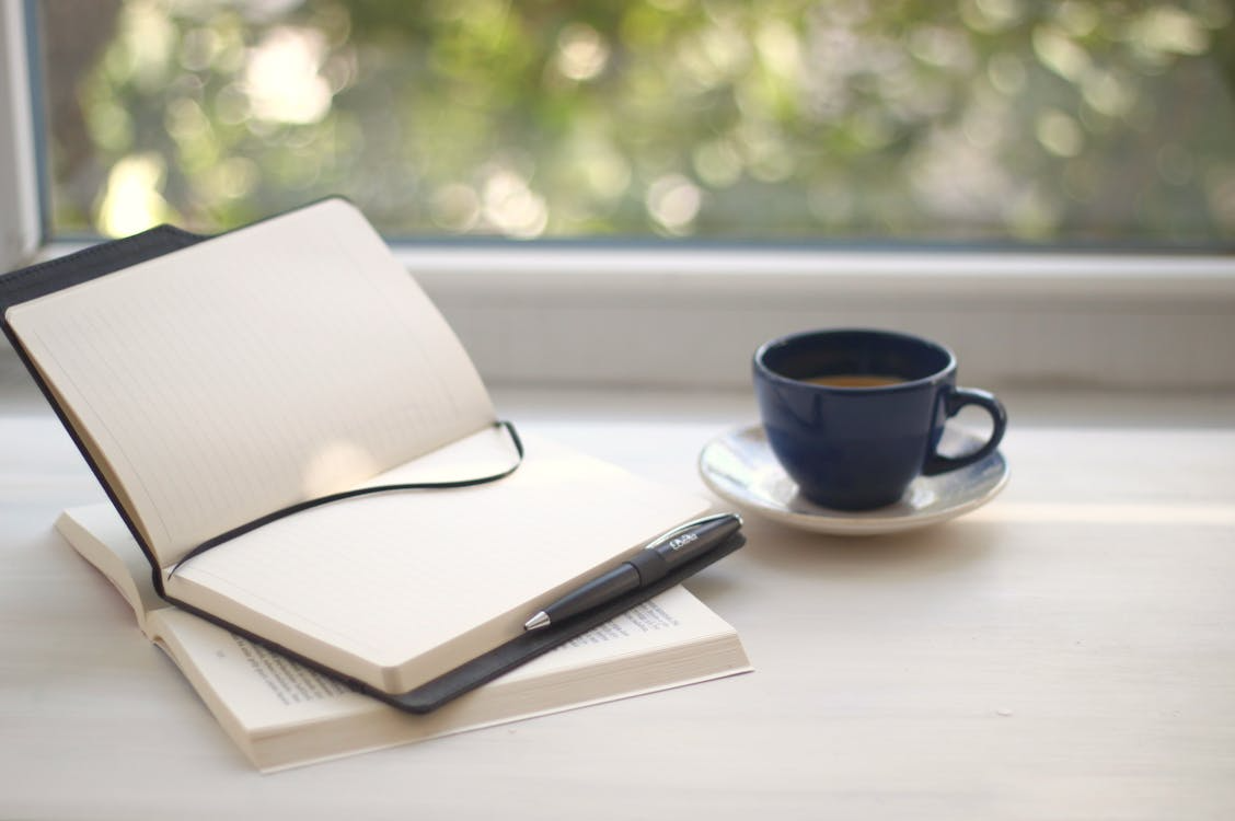 Notebook, pen, and coffee cup for mindful journaling and time perception hacks.